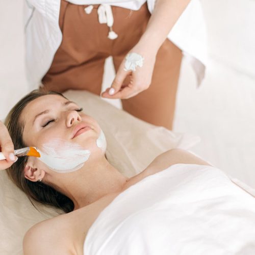 A Person Applying Facial Mask on Woman's Face